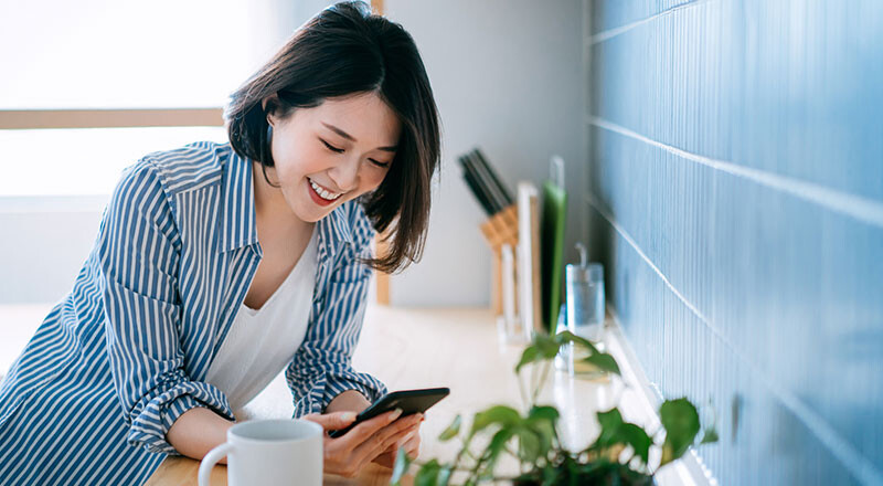 Woman smiling while using a smartphone, UOB Singapore dollar fixed deposit product imagery
