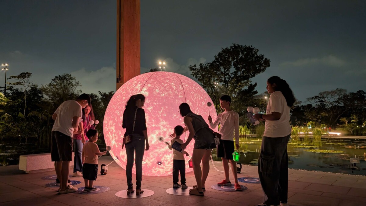 Families gather around a glowing pink celestial sphere on the Celestial Trail at Science Centre Singapore during Celestial Nights
