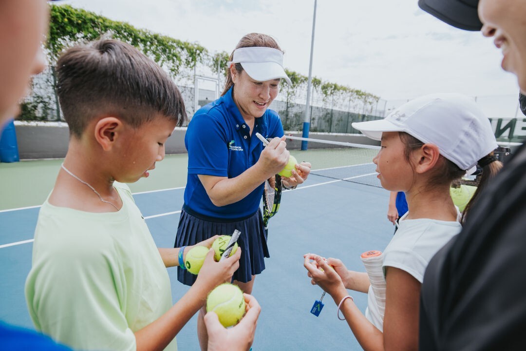 Singapore Tennis Open player signing tennis balls for young fans on court
