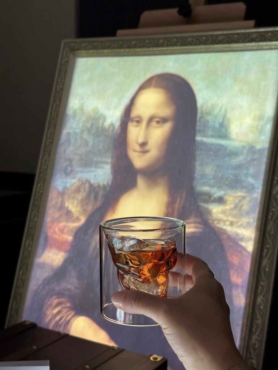 Welcome drink in a skull glass in front of a Mona Lisa canvas at 7 Paintings, Conrad Singapore Marina Bay