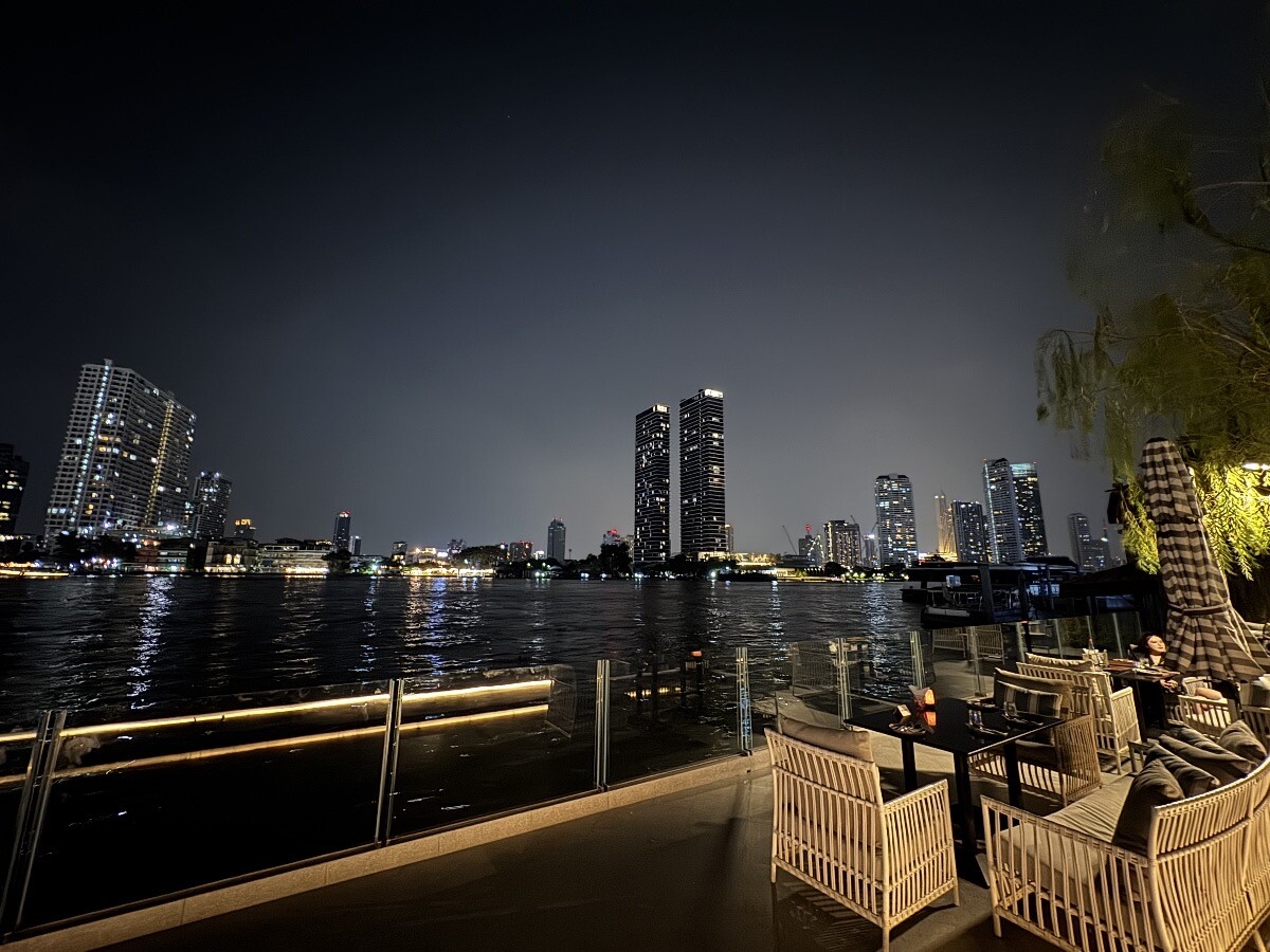 Seated right next to the Chao Phraya River while enjoying the view of night skyline of Bangkok, Thailand