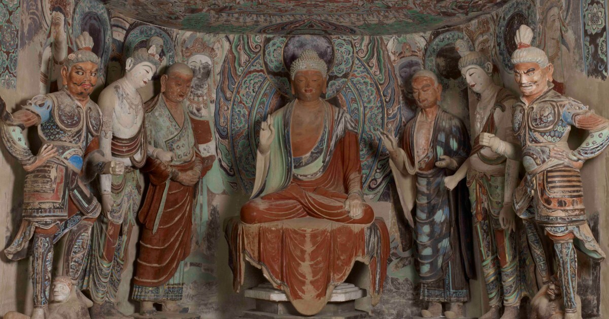 Painted Mogao cave niche with seated Buddha flanked by disciples, bodhisattvas and guardians