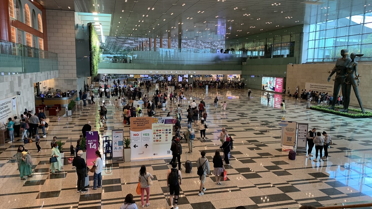 Travellers walk through the Changi Airport Terminal 3 arrival hall towards immigration past a sign asking if they have submitted their SG Arrival Card