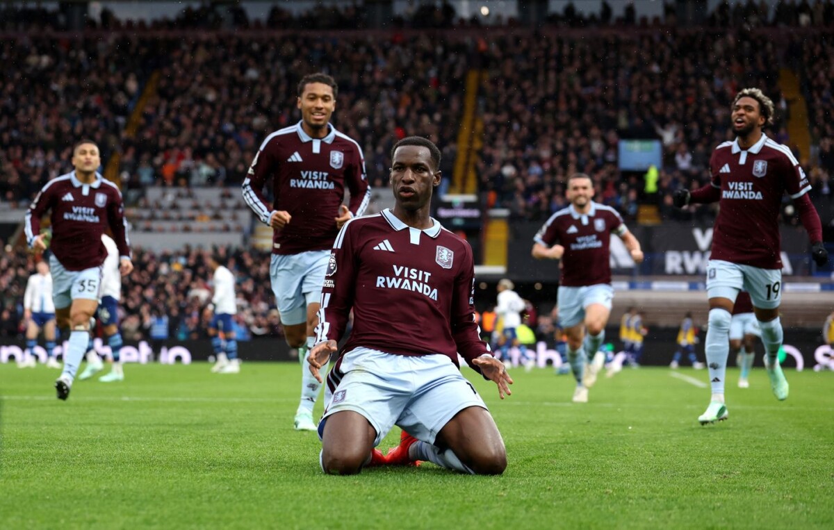 Nicolas Jackson on his knees celebrating as Aston Villa team-mates run towards him