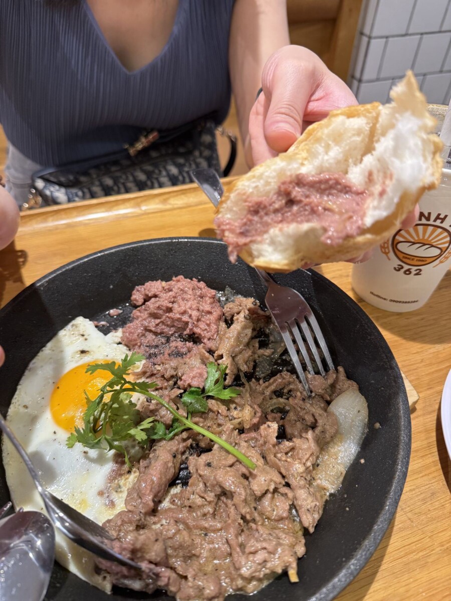 Tearing the baguette and scooping pate, sizzling beef and egg at Banh Mi 362 Saigon