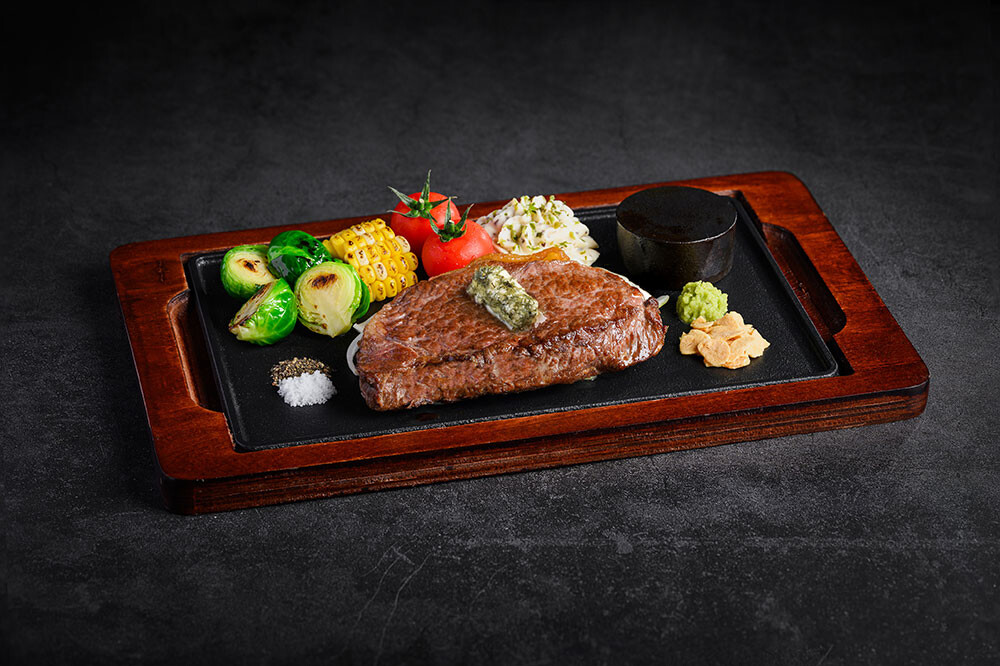 Seared sirloin with herb butter, sides and hot stone pellet on a teppan plate