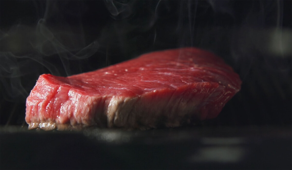 Close-up of a thick steak sizzling on a hot teppan surface