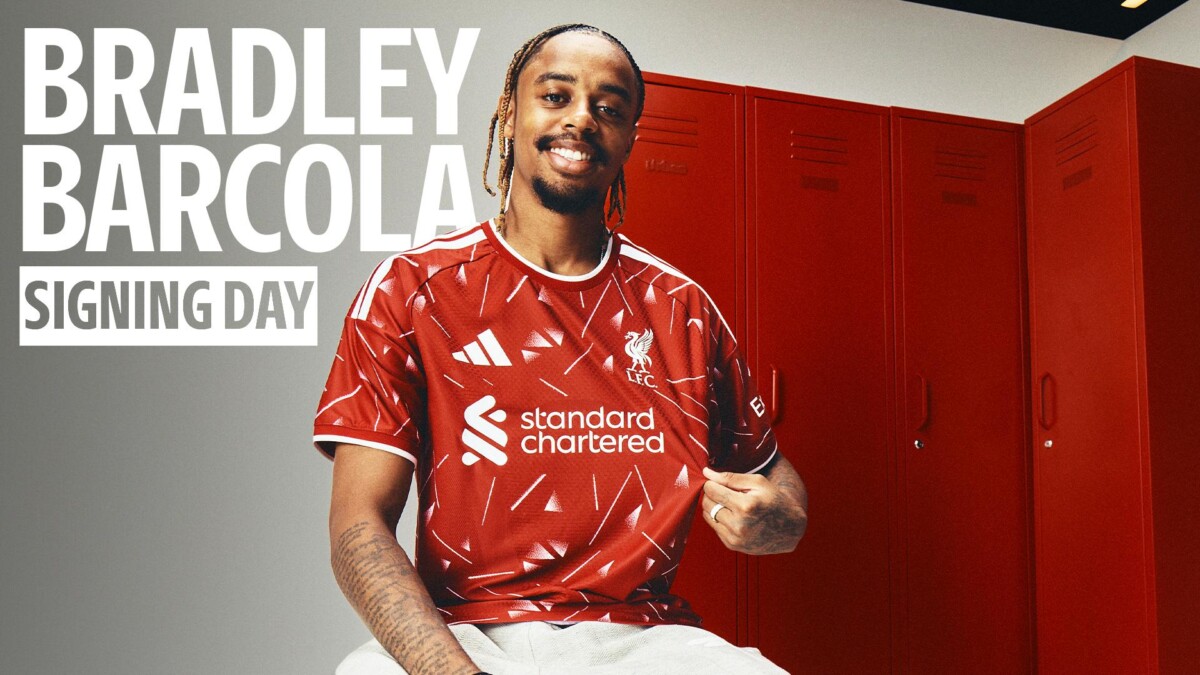 Bradley Barcola smiles in a Liverpool home shirt on signing day