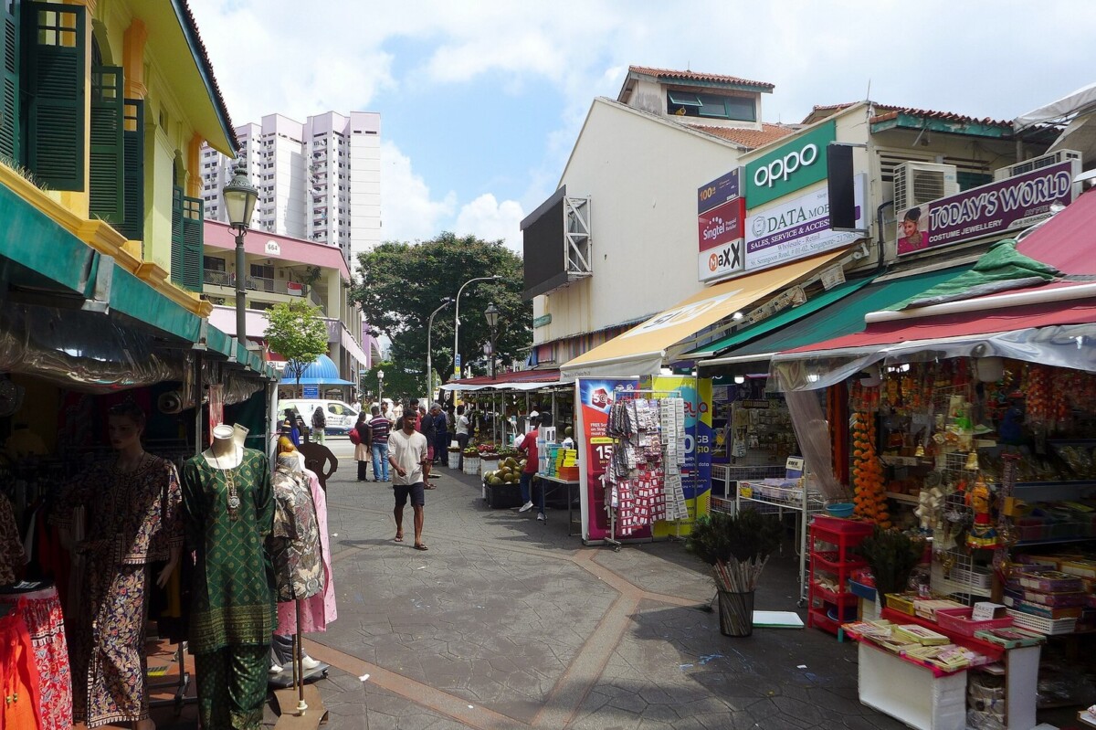 Campbell Lane seen from above, with mannequins in saris outside a yellow shophouse on the left and stalls under red and teal awnings on the right
