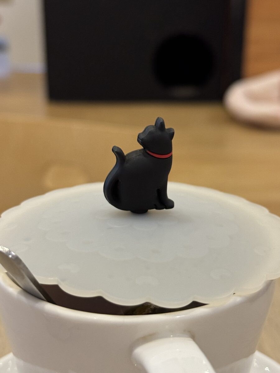 Black cat figurine perched on the lid of a coffee cup at The Cat Cafe Bugis