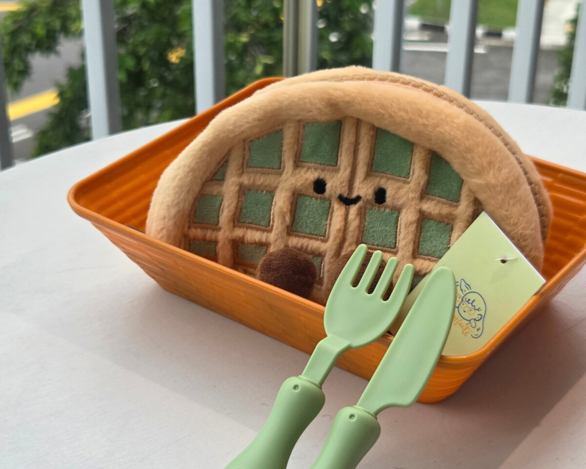 Waffle-shaped plush pouch from a local maker in an orange basket with toy cutlery