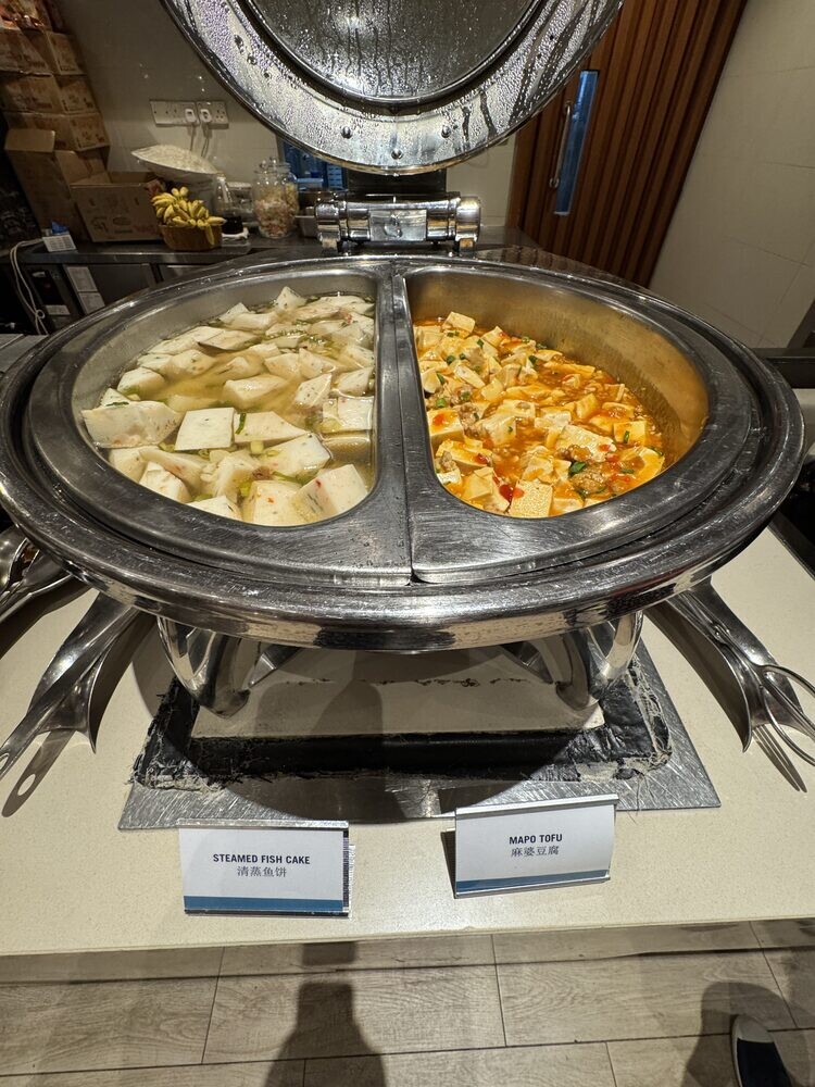 Divided chafing dish with chye poh omelette on one side and pale cubes on the other, printed dish labels in front
