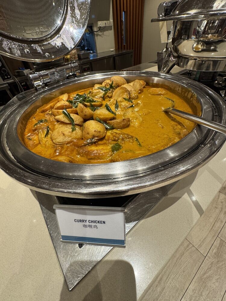 Chafing dish of Curry Chicken in yellow curry gravy with a ladle, dish label in front