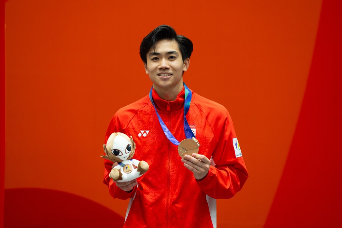 Darren Yap holds his Asian Games 2026 taekwondo poomsae bronze medal and mascot plush