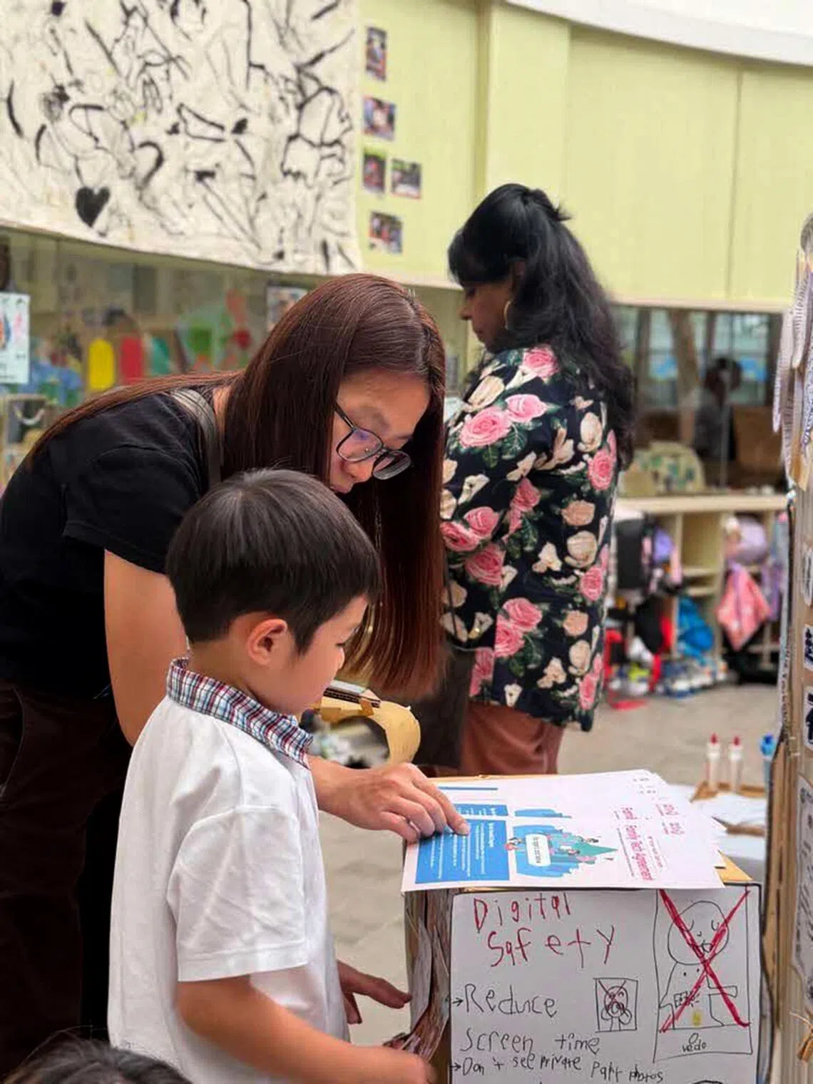 Parents and a child with a digital safety poster at an E-Bridge Celebration of Learning event