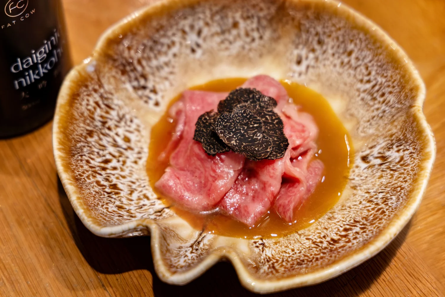 Kansai-style wagyu ribeye sukiyaki topped with truffle slices in a ceramic bowl at Fat Cow