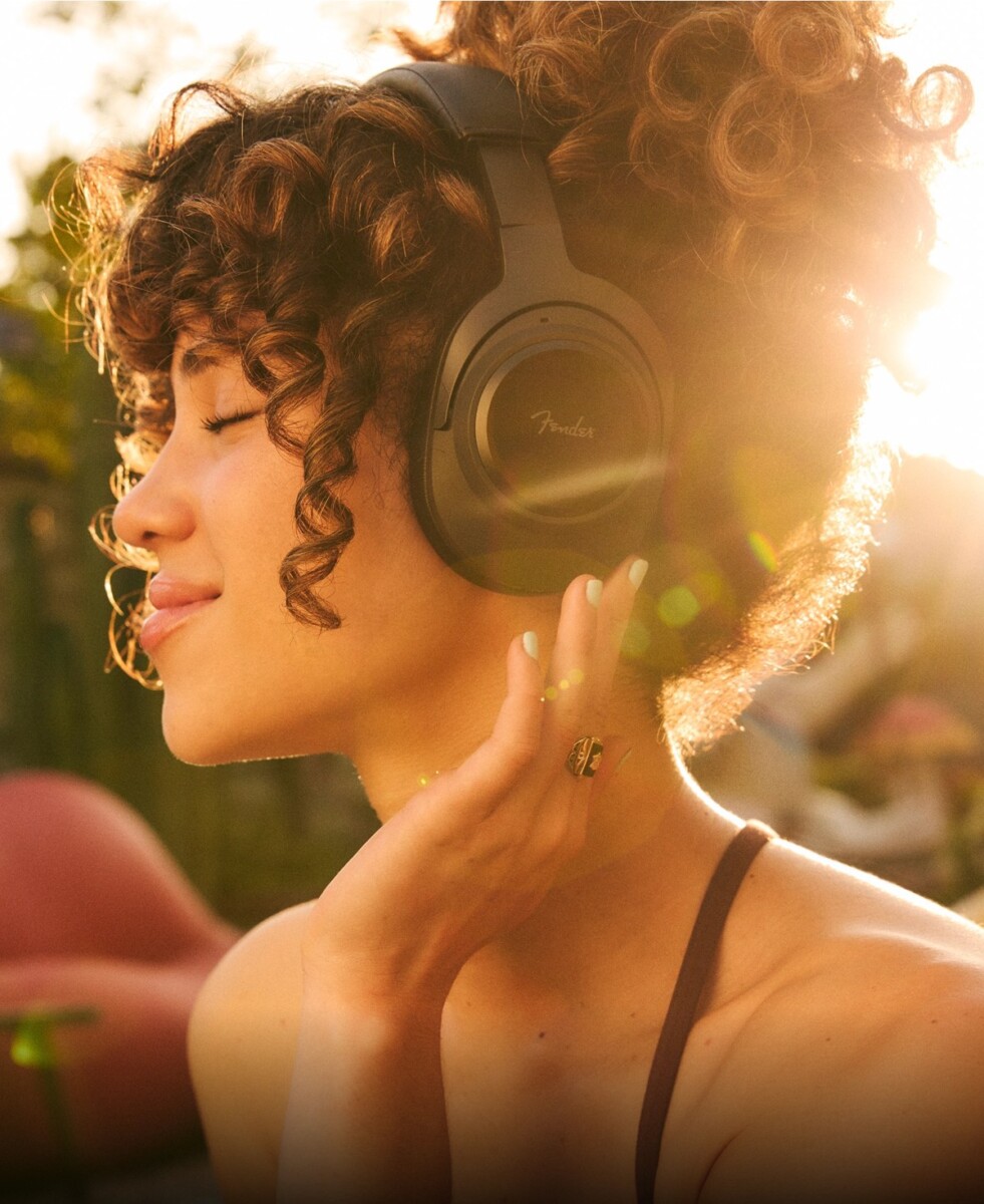 Woman wearing black Fender Audio Mix wireless headphones with replaceable battery and cushions