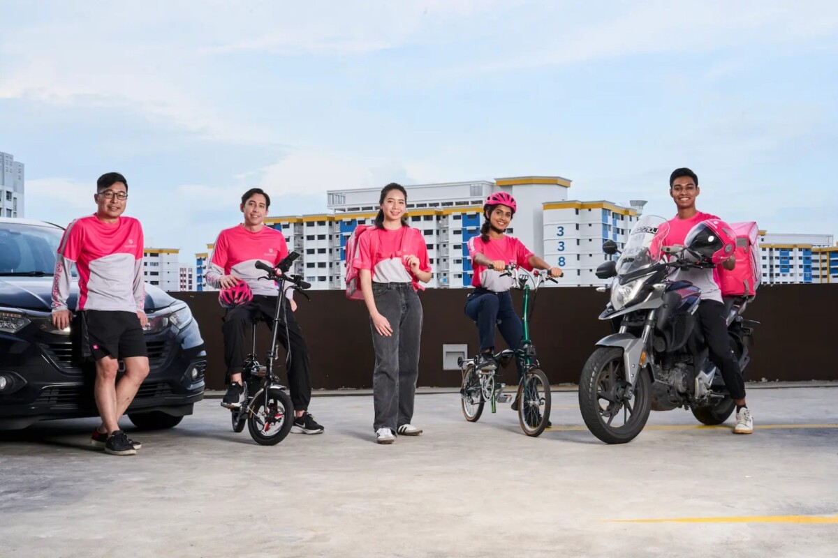 Five foodpanda riders in pink jerseys with bicycles, e-bikes, a motorcycle and a car at a carpark