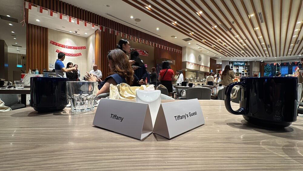 Dining room at Four Points Eatery with reserved table cards and cups on a set table, buffet counters in the background