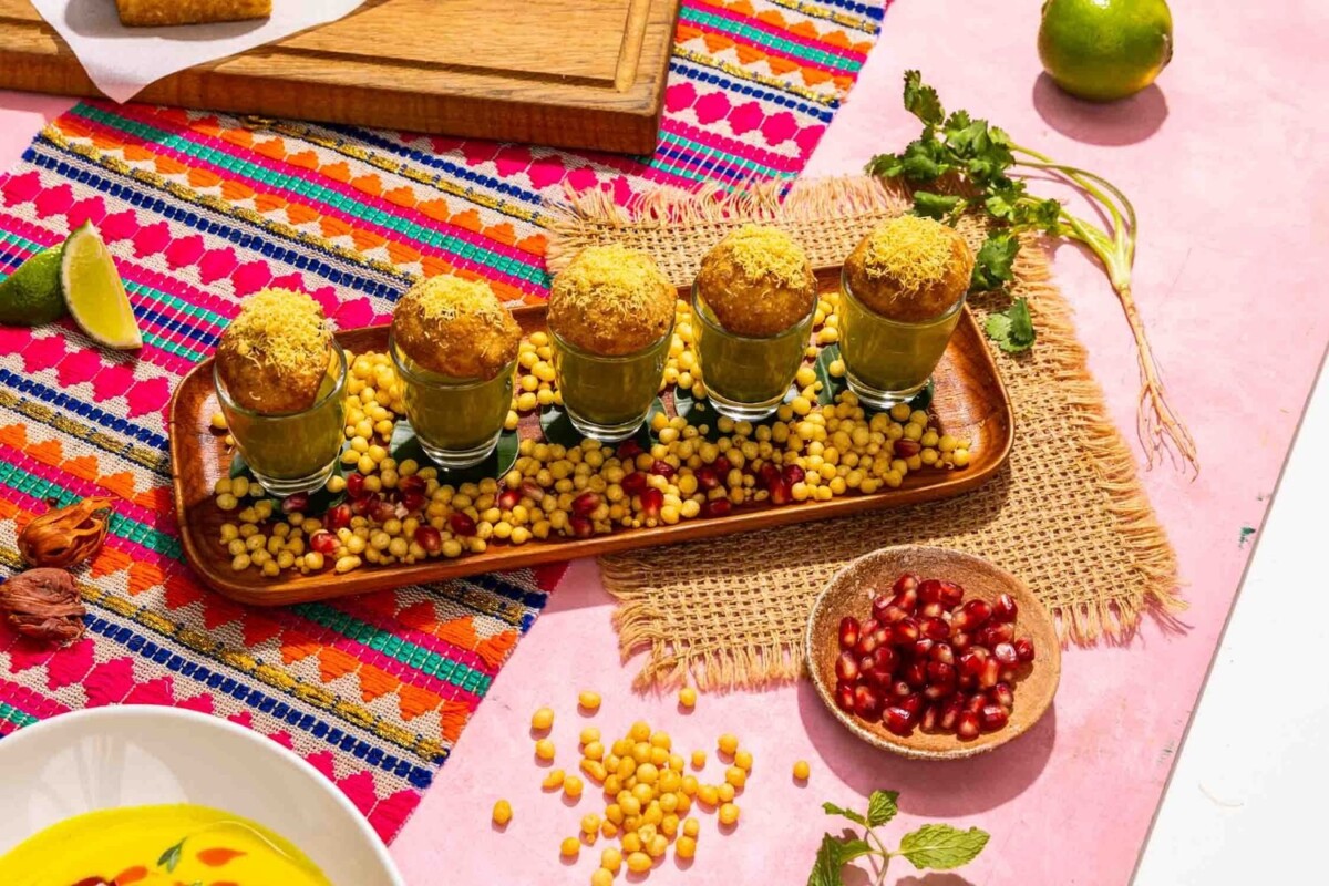 Pani puri with five glasses of green sauce on a wooden tray at Gully