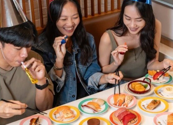 Diners sharing sushi plates at Genki Sushi