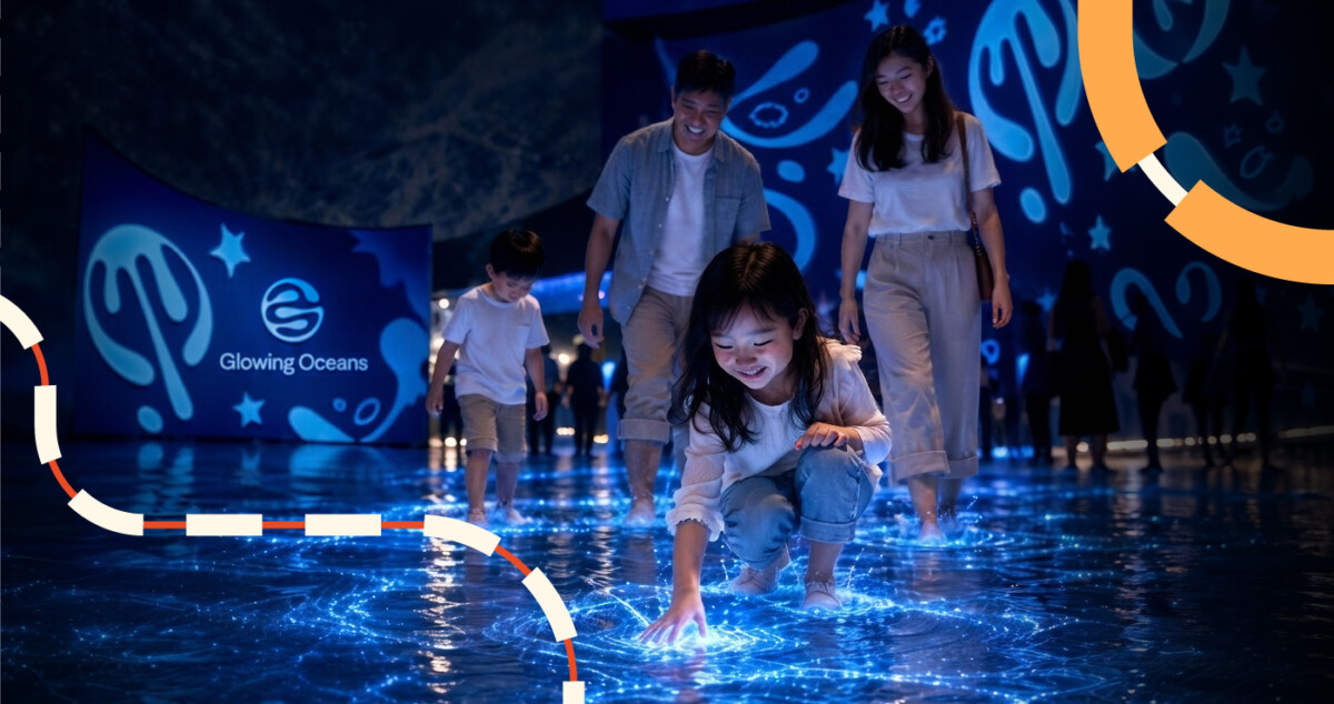 Children and adults wade through glowing blue bioluminescent water in the Glowing Oceans lagoon
