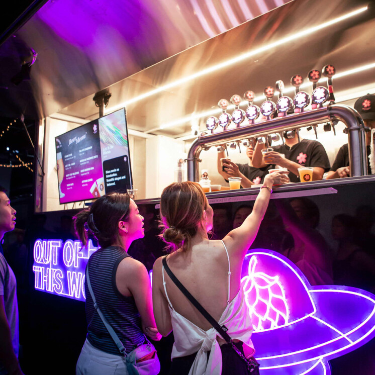 Two women at the neon-lit Pink Blossoms Brewing BeerTruck taps