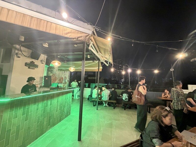 Rooftop bar with green neon bar front and string lights at Heineken First Sip House