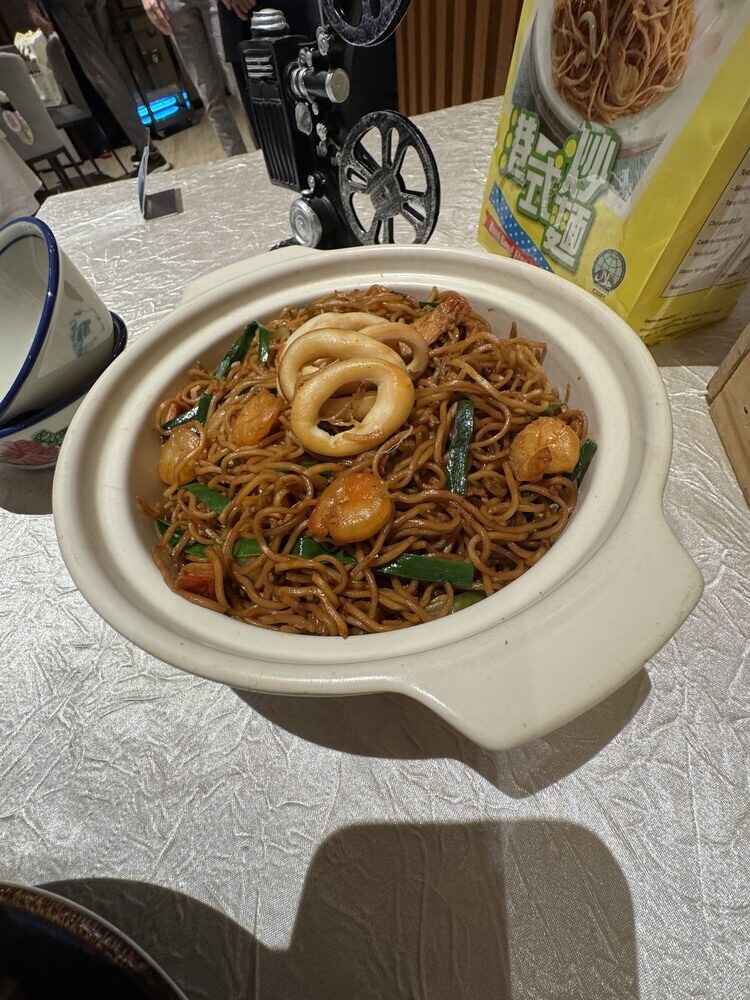 Claypot of Heritage Seafood Hong Kong Noodles with squid rings and prawns, served on a marble counter
