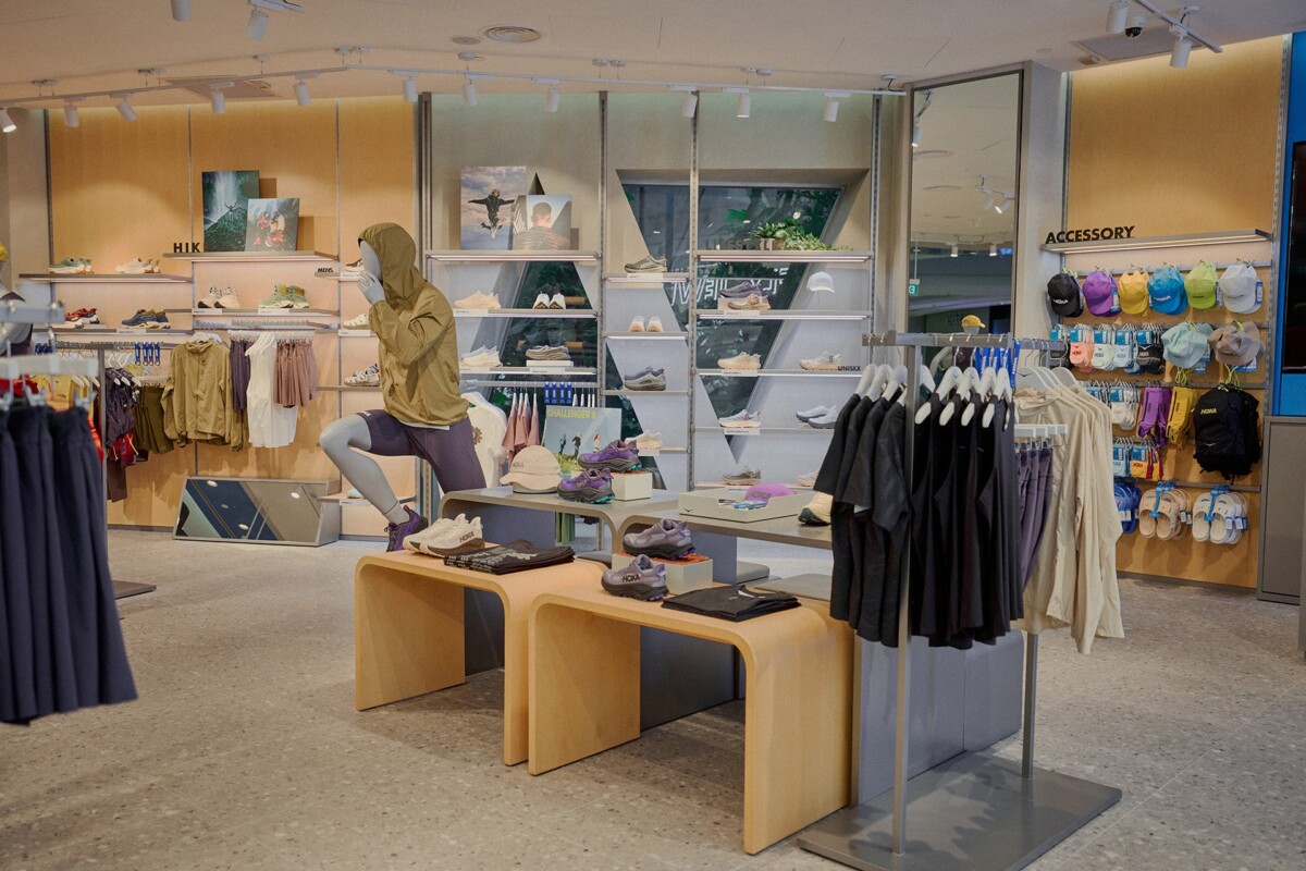 HOKA Jewel store display with a mannequin in hiking gear, apparel racks and a cap wall