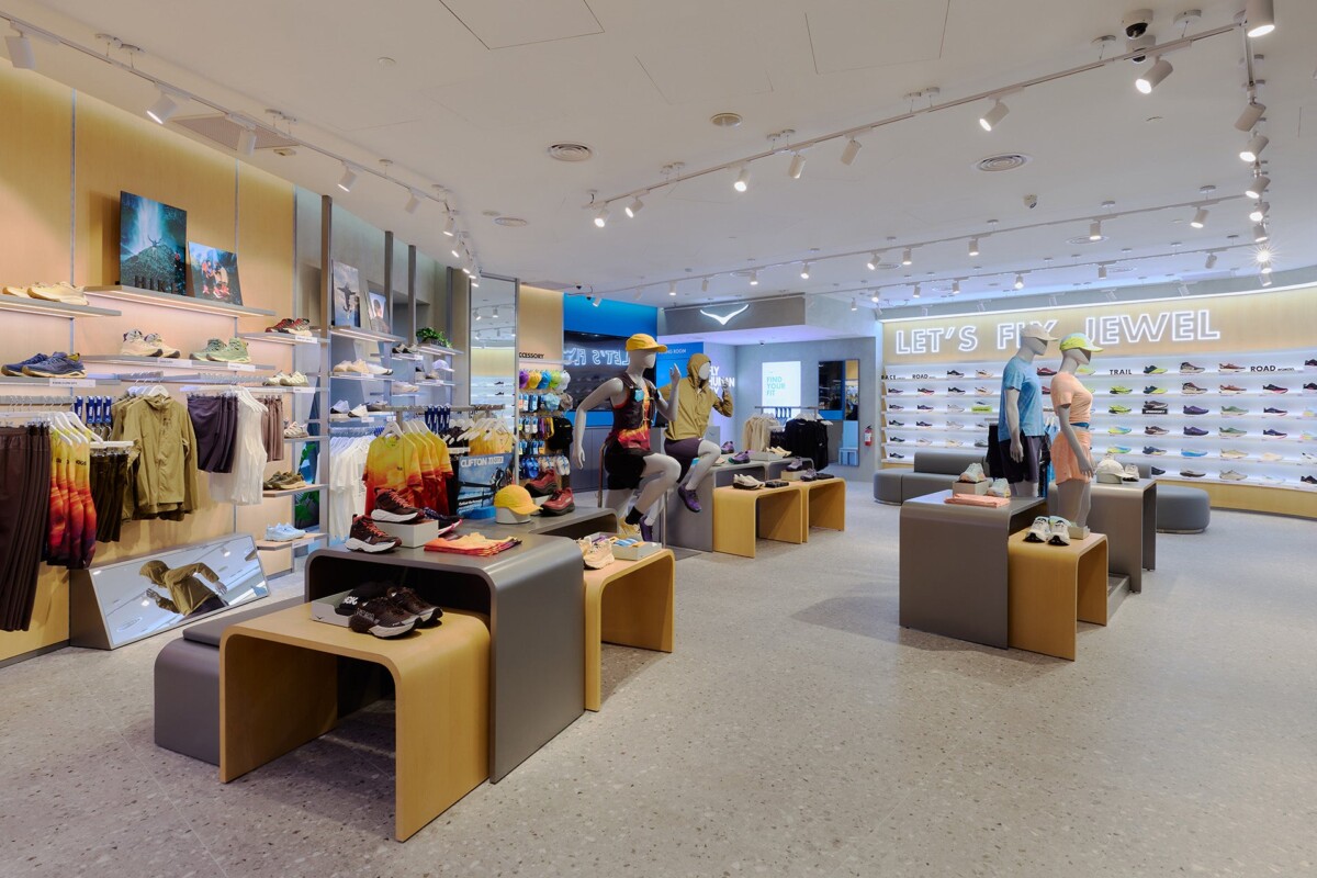 Interior of the HOKA store at Jewel Changi Airport with a lit Let's Fly Jewel shoe wall