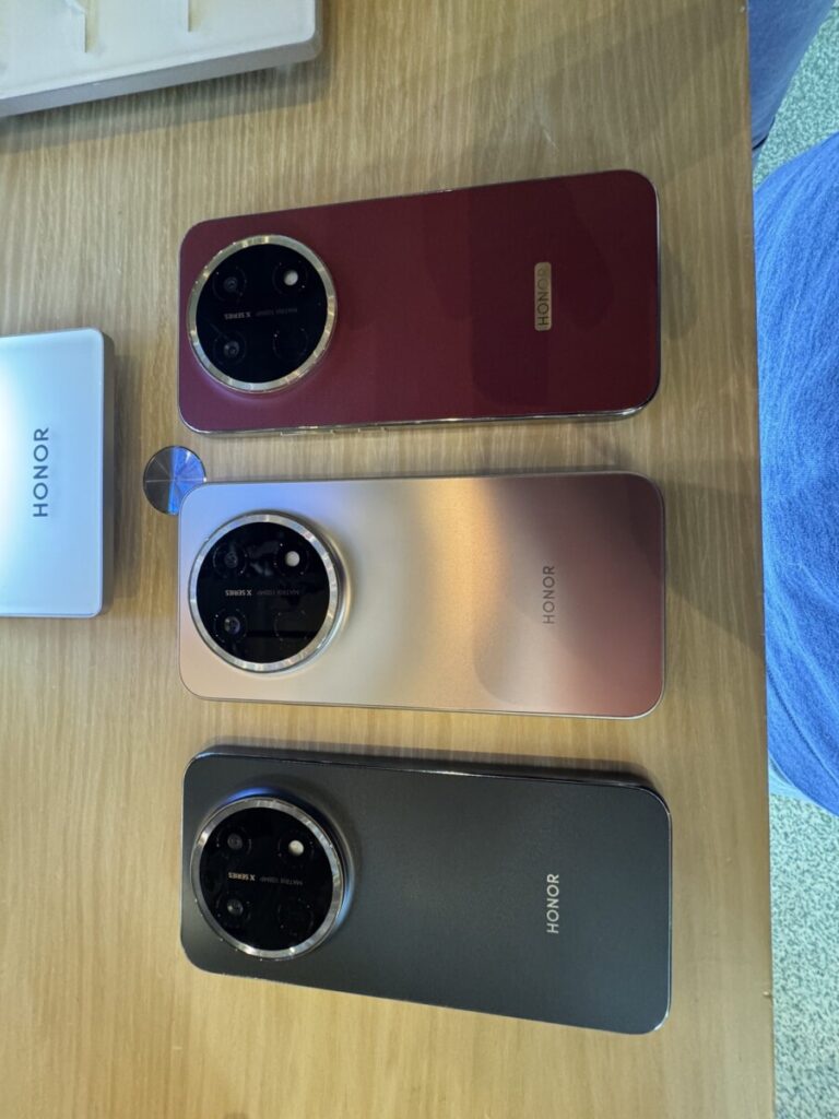 HONOR X9e Pro units in Reddish Brown, Dawn Gold and Midnight Black on a demo table