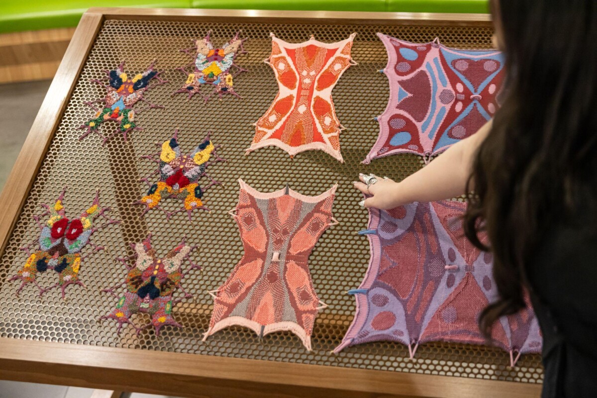 Visitors touching the knitted textile pieces laid out on a honeycomb metal table at Jurong Library