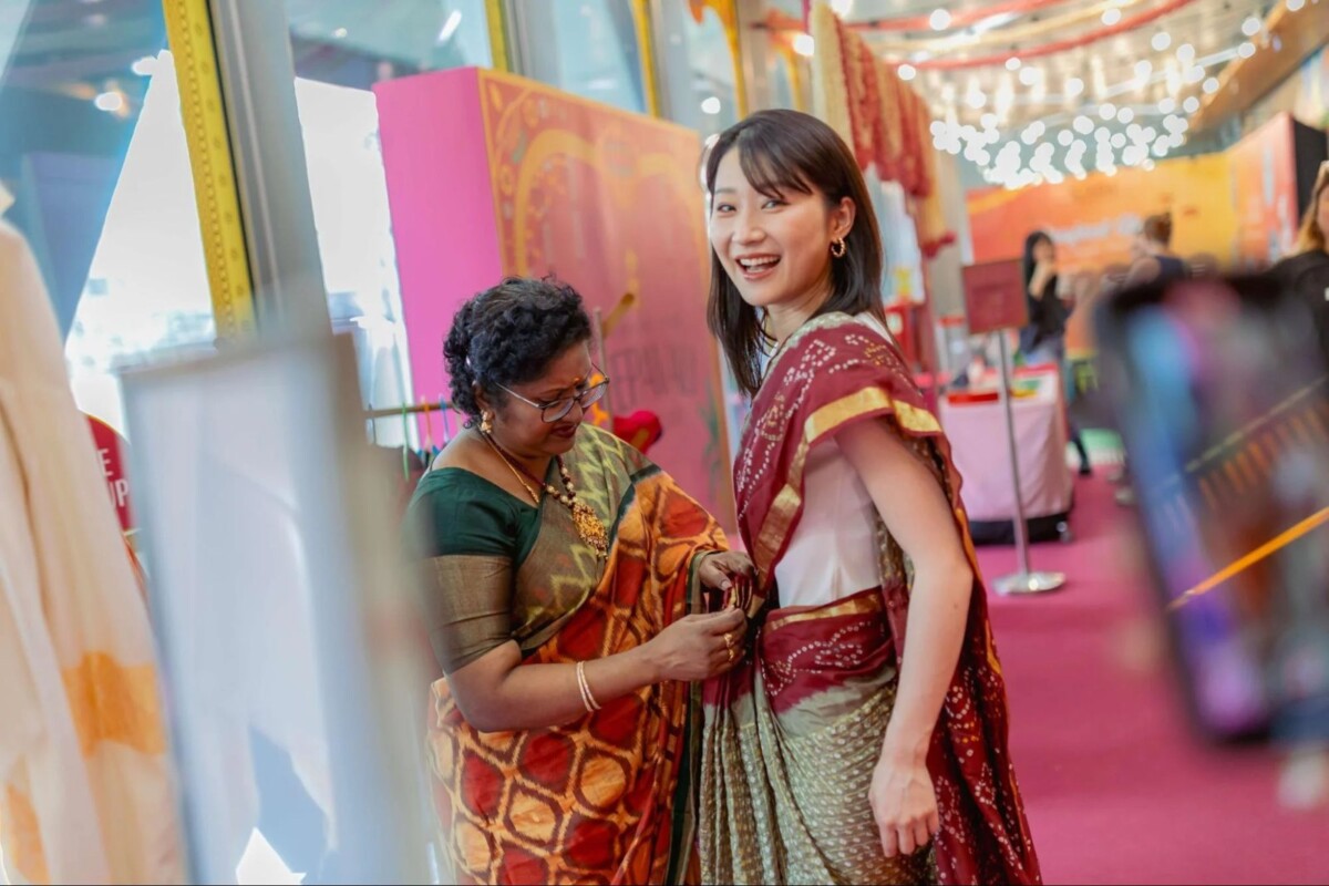 Visitor being helped into a saree at the Indian Heritage Centre Deepavali Open House dress-up station