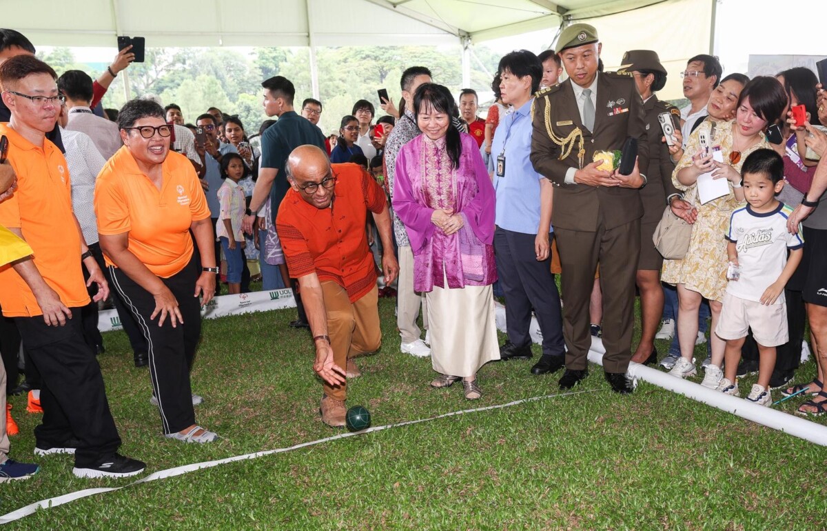 Visitors gather around a lawn game under a tent at a past Istana Open House