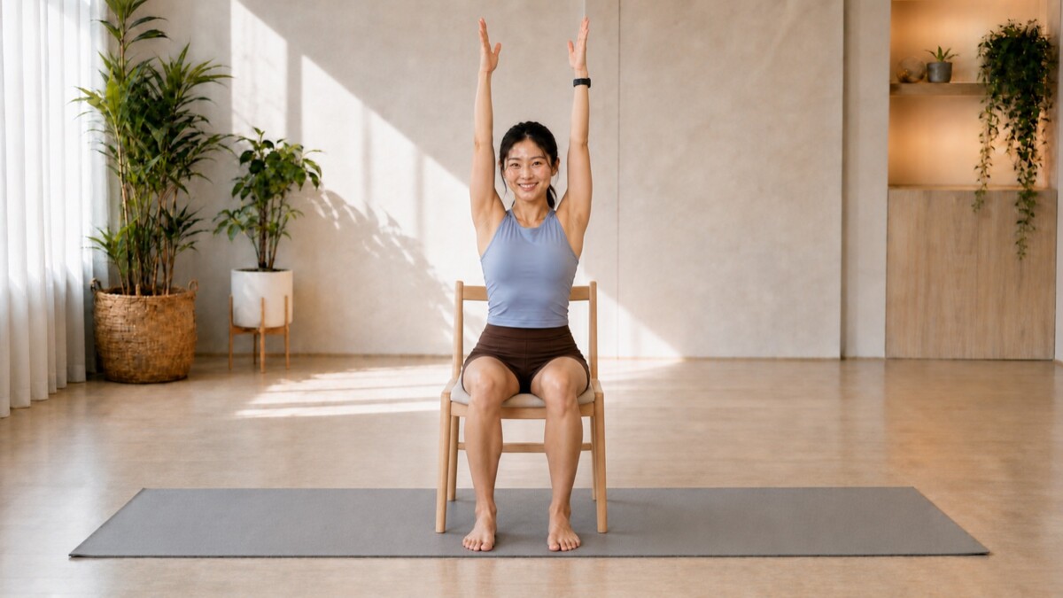 Jade Yeo reaching both arms overhead in Seated Mountain on a stable chair