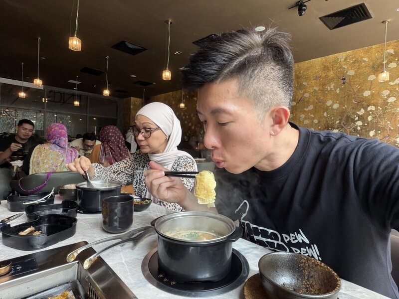 Willie eating a bean curd roll from the Pong Tauhu broth at JING Halal Hotpot and Grill