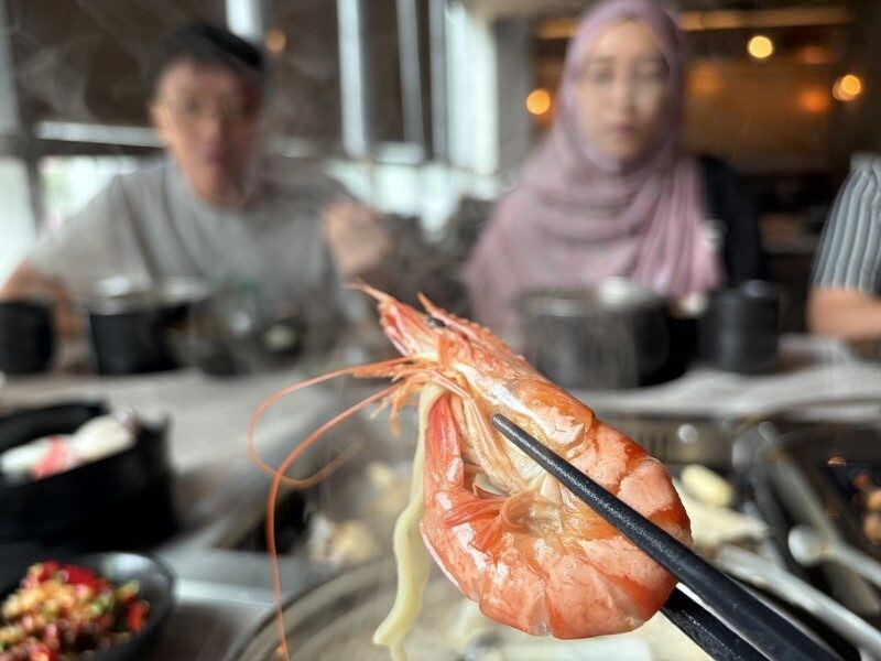 Cooked tiger prawn lifted from the broth, vivid orange and plump, at JING Halal Hotpot and Grill