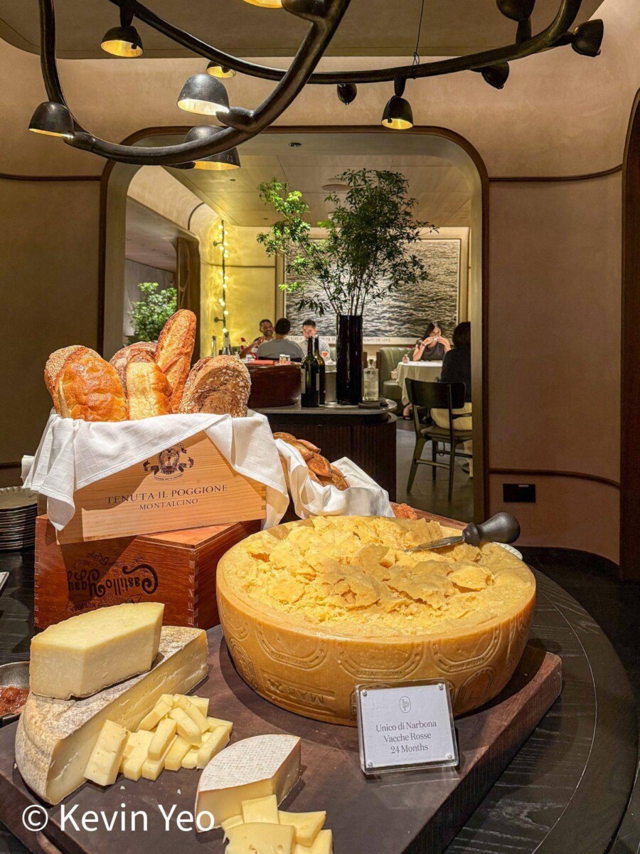 Cheese station at Le Pristine Singapore featuring a full Parmigiano wheel and assorted cheeses with breads