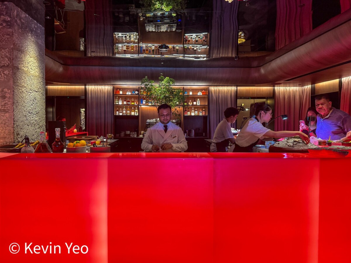 Glowing red bar counter at Le Pristine Singapore with the seafood station behind it