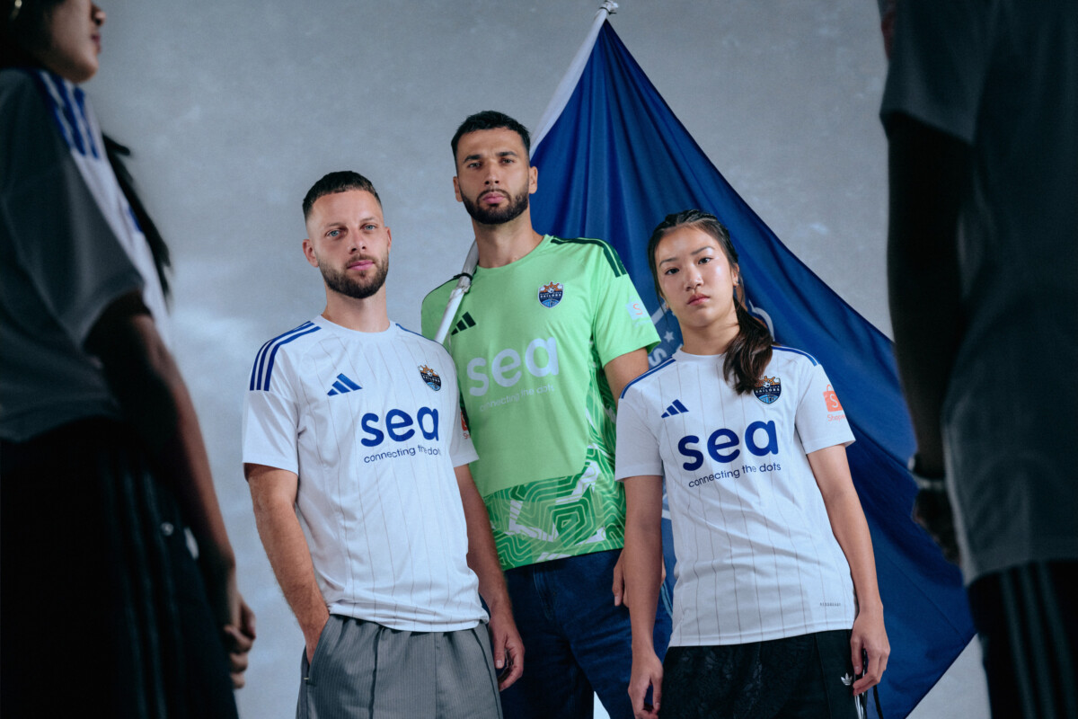 Lion City Sailors players in white home kit with goalkeeper holding a club flag