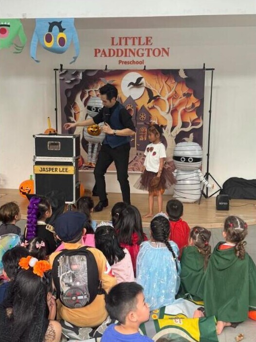 Magic show at Little Paddington Preschool's Halloween celebration in front of a Halloween backdrop