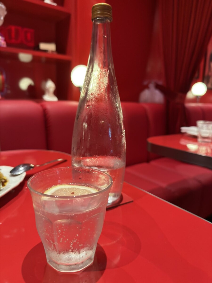 Free flow water bottle and a glass with lemon on a red table