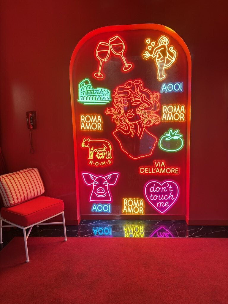 Neon wall art with a Medusa head, the Colosseum and Roma Amor signs