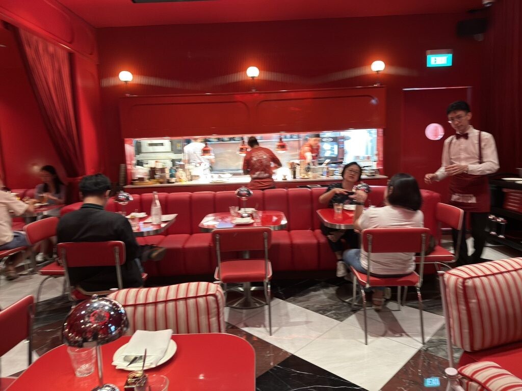 Open kitchen and red banquettes in the dining room at Medusa Singapore