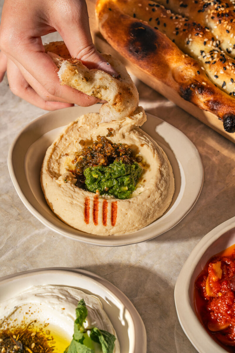 Hummus topped with a green herb sauce, served with torn flatbread at Petra