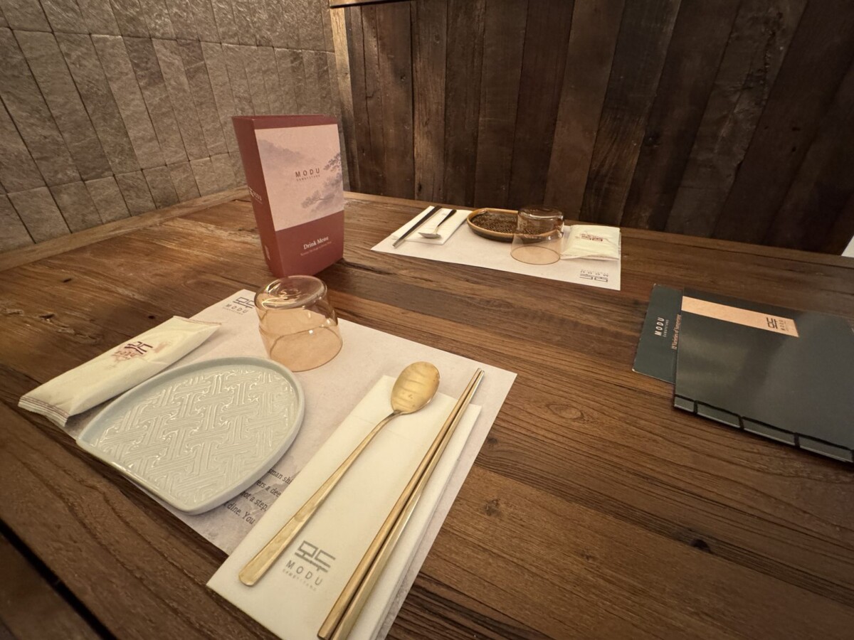 MODU Samgyetang table setting with celadon side plate, brass spoon and chopsticks, and branded placemat