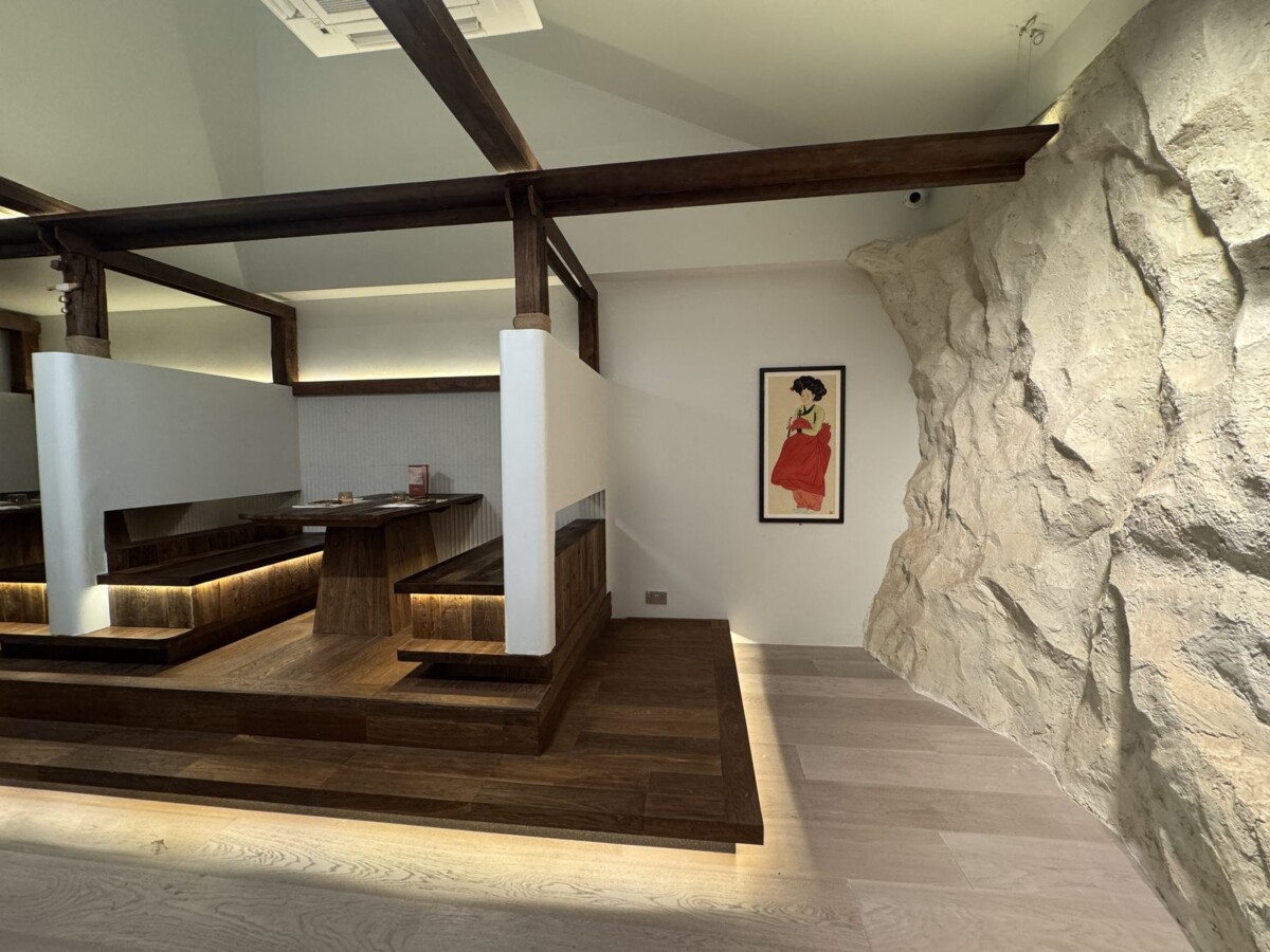 Hanok-inspired interior at MODU Samgyetang with timber beams and a raw granite feature wall