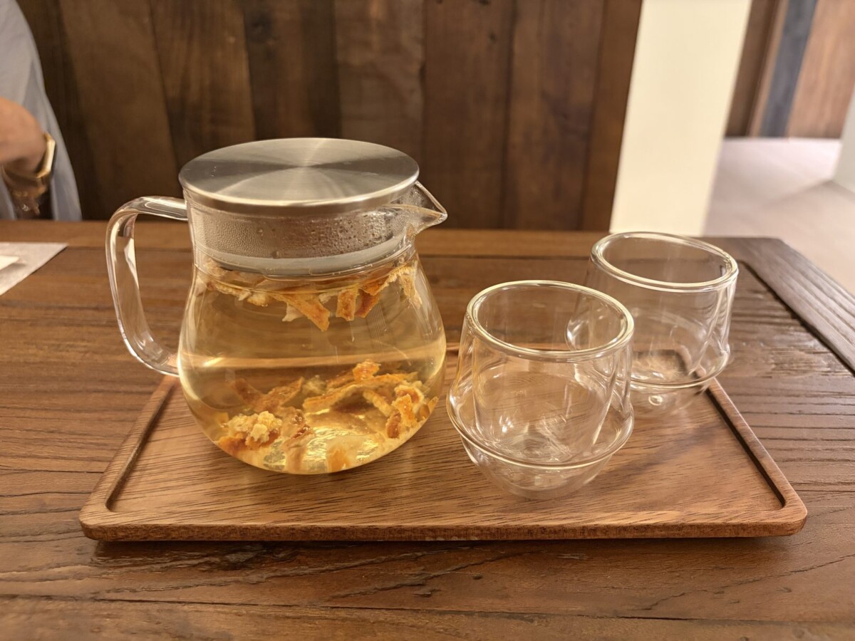 Tangerine tea served in a glass pot with two double-walled glass cups on a wooden tray at MODU Samgyetang