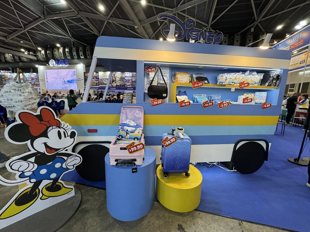 Disney branded booth at WTS Travel with luggage on display and price tags, Minnie Mouse cutout in the foreground